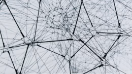 Abstract network graphic of interconnected black lines, and nodes creating a 3D geometric web on a light background.