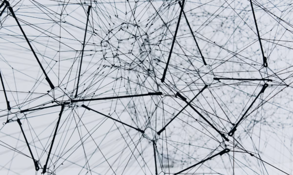 Abstract network graphic of interconnected black lines, and nodes creating a 3D geometric web on a light background.